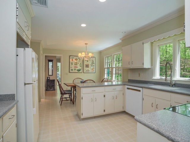 kitchen featuring white appliances, a sink, a chandelier, a peninsula, and crown molding