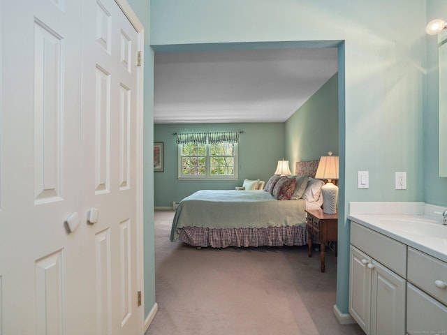 bedroom with a sink and light carpet