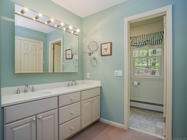 bathroom with a baseboard heating unit, double vanity, and baseboards