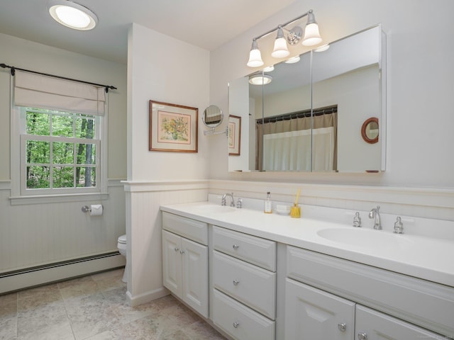 bathroom with baseboard heating, toilet, double vanity, a wainscoted wall, and curtained shower