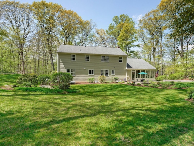 rear view of property featuring a lawn, a chimney, and a patio