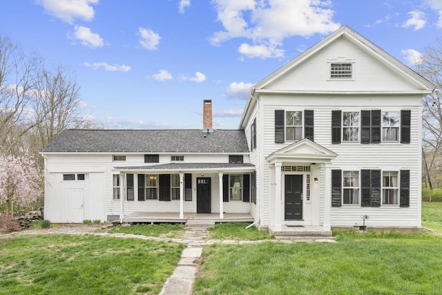 greek revival inspired property featuring a porch, a chimney, a shingled roof, and a front lawn