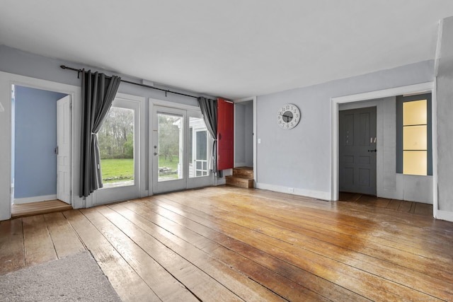 unfurnished living room featuring baseboards and light wood finished floors