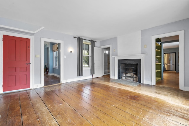 unfurnished living room featuring wood-type flooring, baseboards, and a fireplace with flush hearth