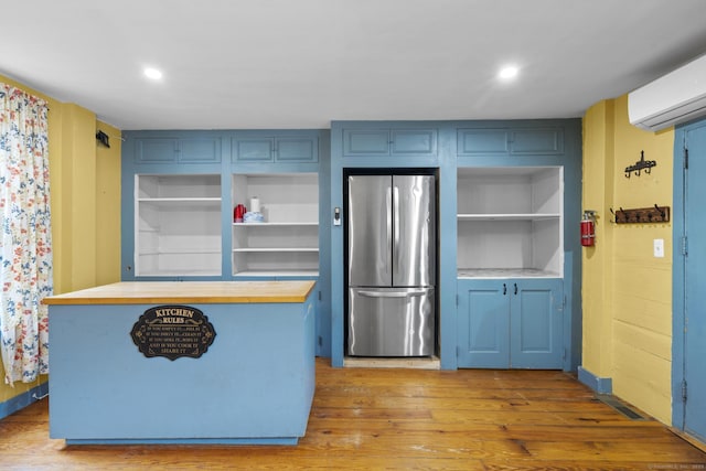 kitchen with open shelves, a wall mounted air conditioner, freestanding refrigerator, baseboards, and wood finished floors
