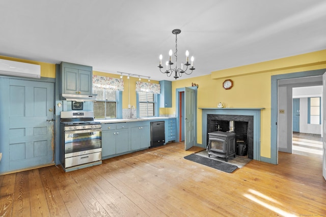 kitchen with a wood stove, a wall mounted air conditioner, stainless steel gas stove, a sink, and dishwasher