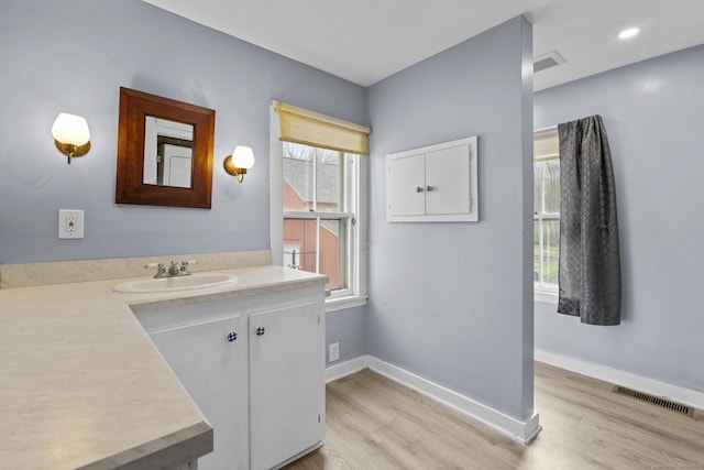 bathroom featuring a healthy amount of sunlight, wood finished floors, and visible vents