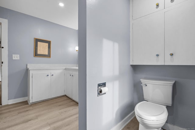 bathroom with baseboards, wood finished floors, toilet, and vanity