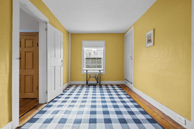 corridor with baseboards and wood finished floors