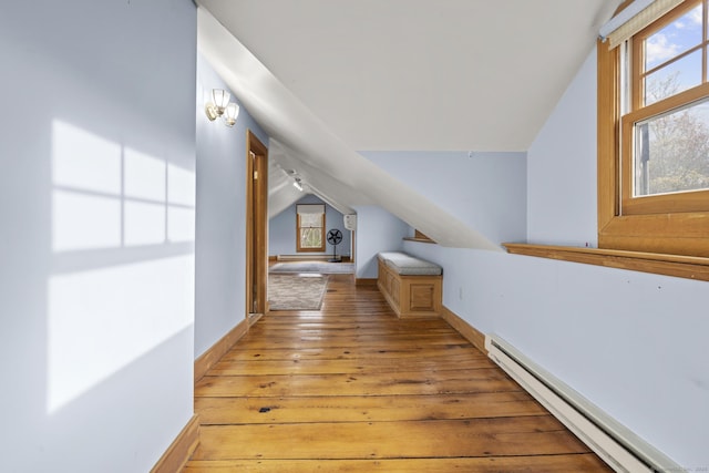 hall with baseboards, vaulted ceiling, baseboard heating, and light wood-type flooring