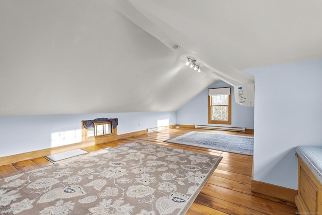bonus room with wood-type flooring, baseboards, vaulted ceiling, a baseboard heating unit, and a wall mounted AC