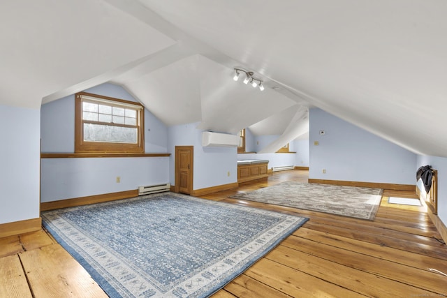additional living space with a wall unit AC, hardwood / wood-style floors, and lofted ceiling