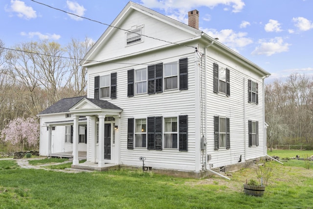 neoclassical home with a front yard and a chimney