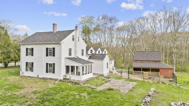 back of property featuring fence, a shingled roof, a sunroom, a chimney, and a lawn