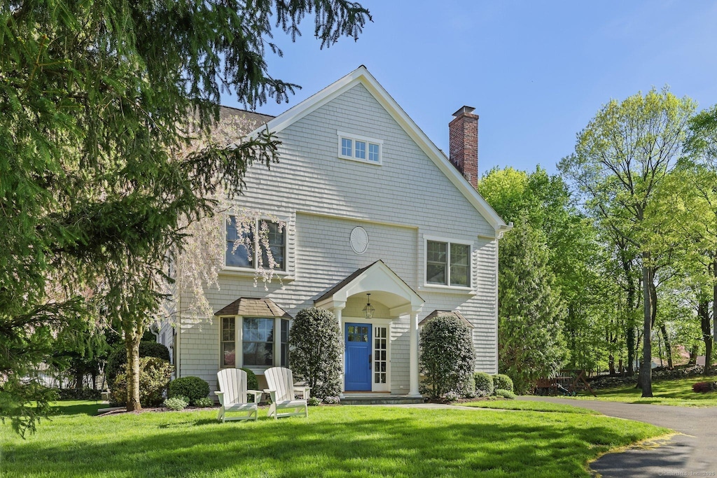 view of front facade featuring a chimney and a front lawn