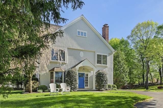 view of front facade featuring a chimney and a front lawn