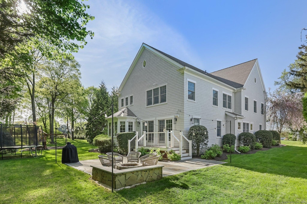 rear view of house featuring a yard, a deck, a patio area, and a trampoline