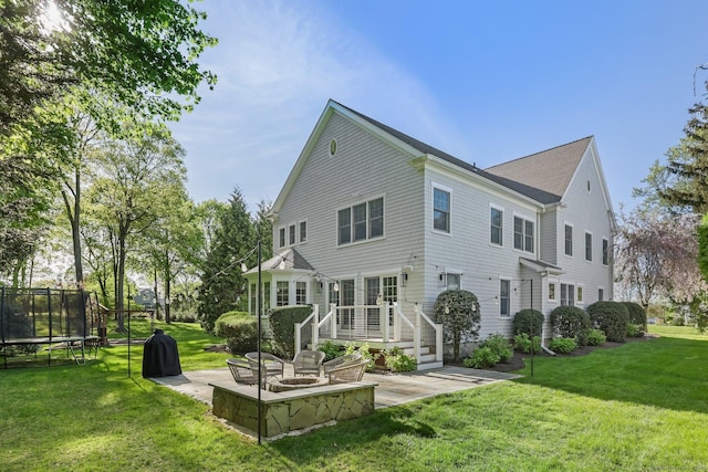 rear view of house featuring a yard, a deck, a patio area, and a trampoline
