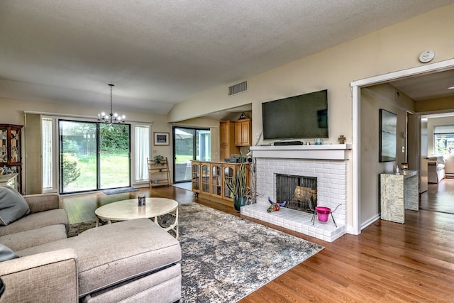 951 Heritage Vlg Unit B, Southbury, CT 06488 - living room with wood finished floors, a brick fireplace, a chandelier, and a textured ceiling