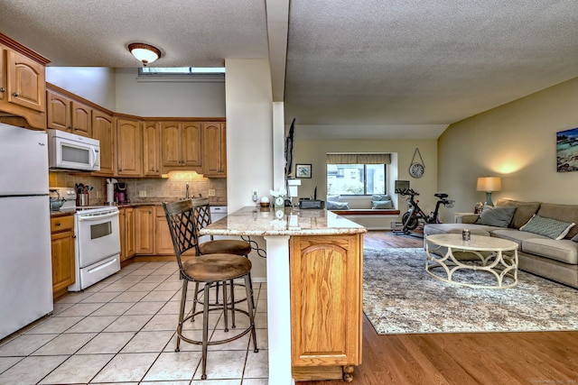 951 Heritage Vlg Unit B, Southbury, CT 06488 - kitchen featuring white appliances, open floor plan, a breakfast bar area, a peninsula, and a textured ceiling