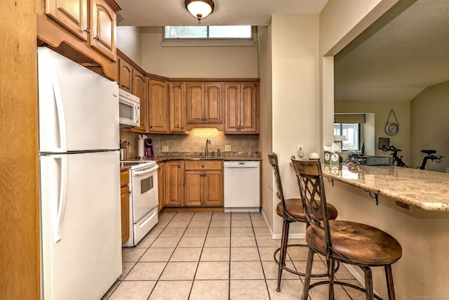 951 Heritage Vlg Unit B, Southbury, CT 06488 - kitchen featuring white appliances, a kitchen breakfast bar, decorative backsplash, light tile patterned floors, and a peninsula