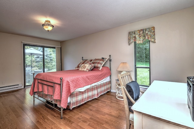 951 Heritage Vlg Unit B, Southbury, CT 06488 - bedroom featuring baseboard heating, access to exterior, wood finished floors, an office area, and a textured ceiling