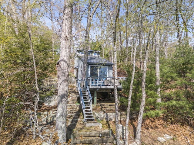 exterior space with stairway, a wooden deck, and metal roof