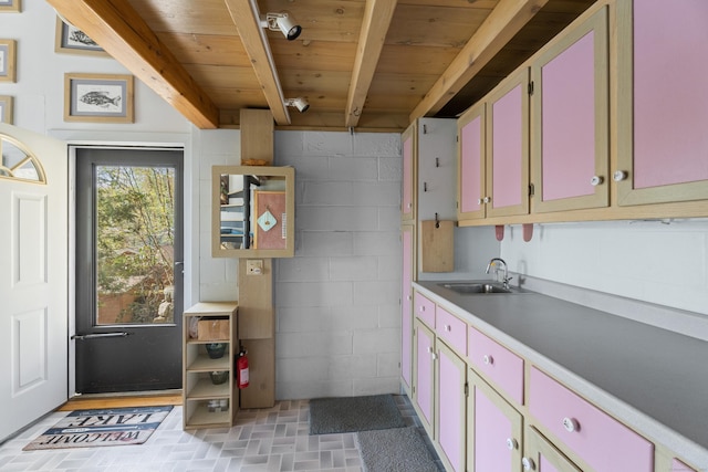 kitchen featuring beam ceiling, a sink, light countertops, brick patterned floor, and wood ceiling