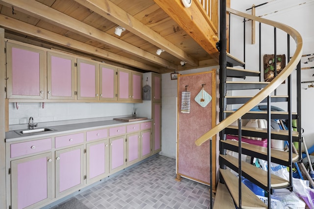 kitchen with beamed ceiling, light countertops, brick floor, wooden ceiling, and a sink