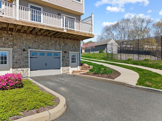 view of community with fence, an attached garage, and driveway