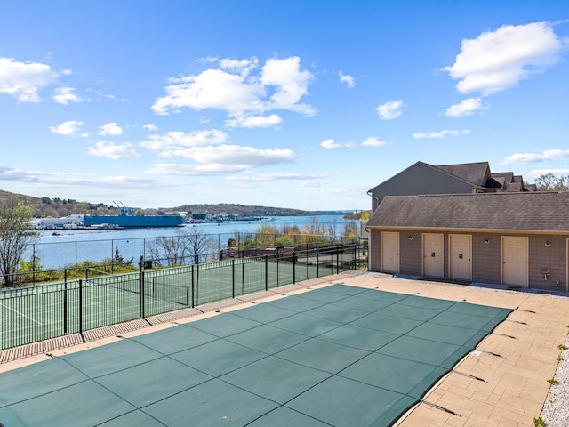 view of swimming pool featuring a fenced in pool, a water view, fence, and a tennis court