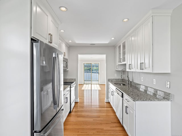 kitchen with a sink, light wood finished floors, white cabinetry, and stainless steel appliances