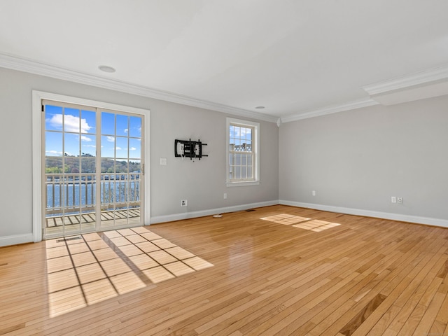 spare room featuring crown molding, baseboards, a water view, and light wood-type flooring