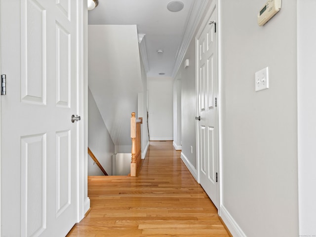hallway featuring baseboards, light wood finished floors, and an upstairs landing