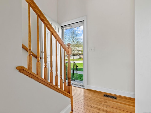 entryway with stairs, baseboards, visible vents, and hardwood / wood-style floors
