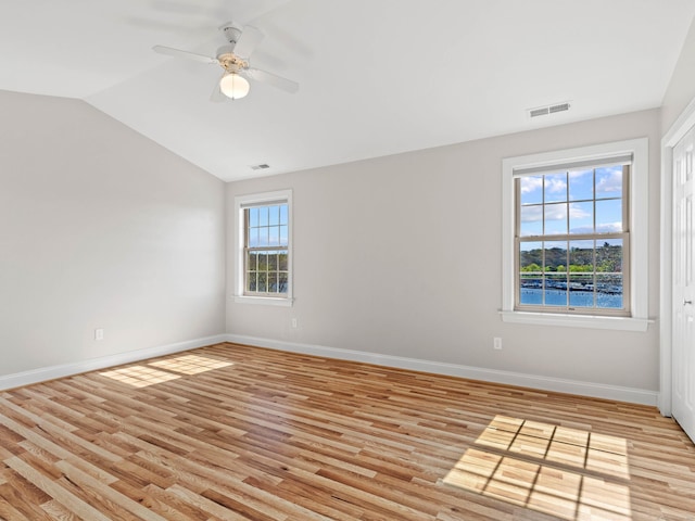 spare room with baseboards, ceiling fan, light wood-style flooring, and lofted ceiling