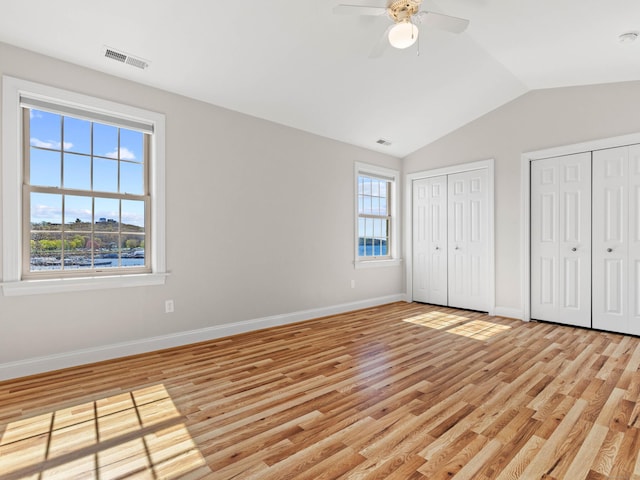 unfurnished bedroom featuring multiple closets, baseboards, light wood-style flooring, and visible vents
