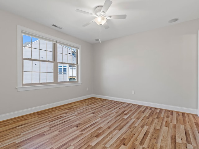 empty room featuring a ceiling fan, baseboards, visible vents, and light wood-type flooring
