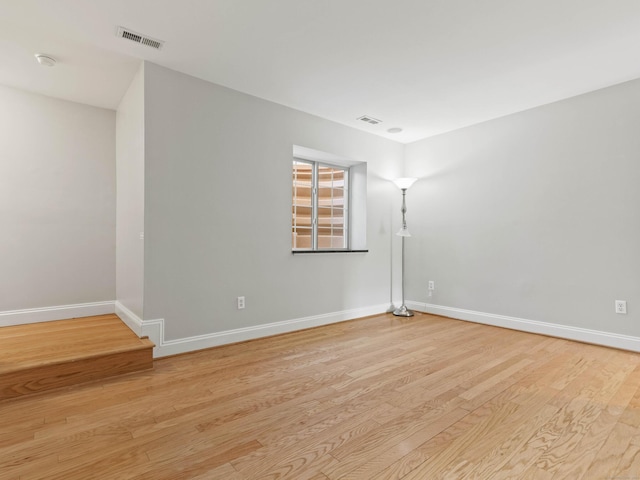 empty room featuring baseboards, visible vents, and light wood finished floors
