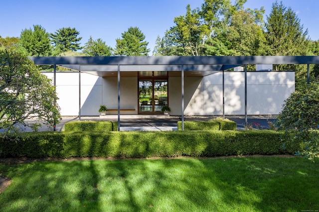 back of house featuring a lawn and stucco siding
