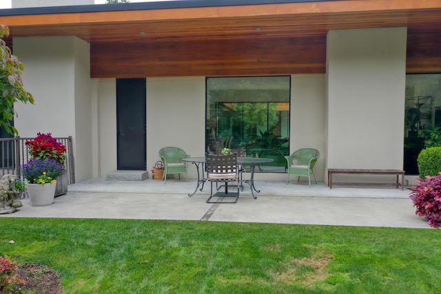 rear view of house with a lawn, a patio, and stucco siding