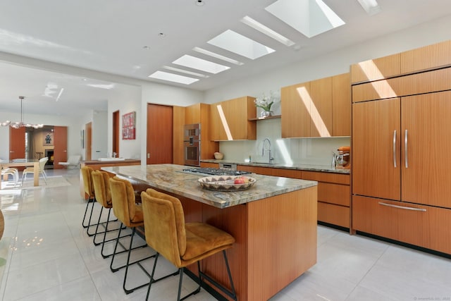kitchen with a sink, a skylight, a kitchen bar, a kitchen island, and built in refrigerator
