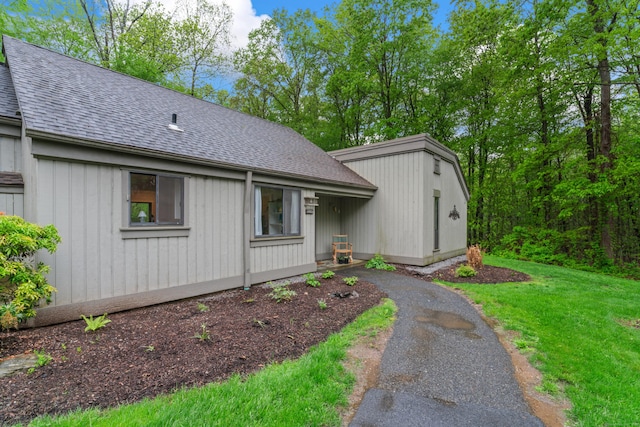 view of front of house featuring roof with shingles and a front lawn
