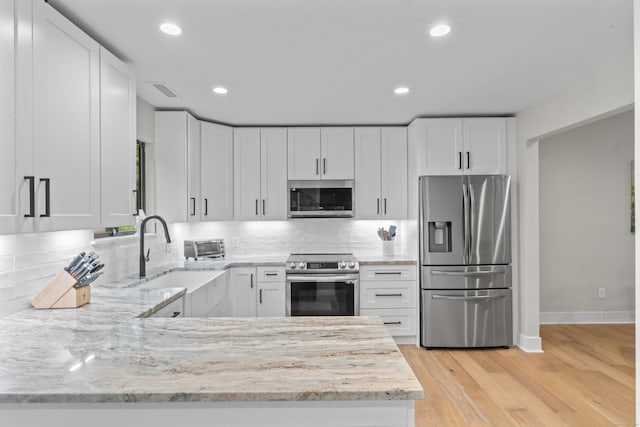 kitchen with stainless steel appliances, light stone counters, white cabinetry, and recessed lighting