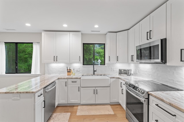 kitchen with appliances with stainless steel finishes, a sink, plenty of natural light, a peninsula, and recessed lighting