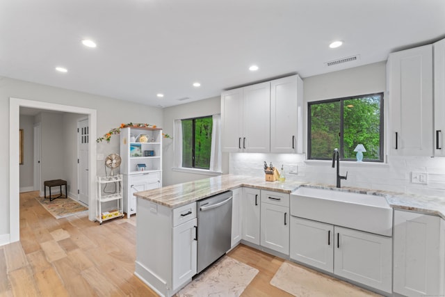kitchen with stainless steel dishwasher, a sink, a peninsula, white cabinets, and recessed lighting