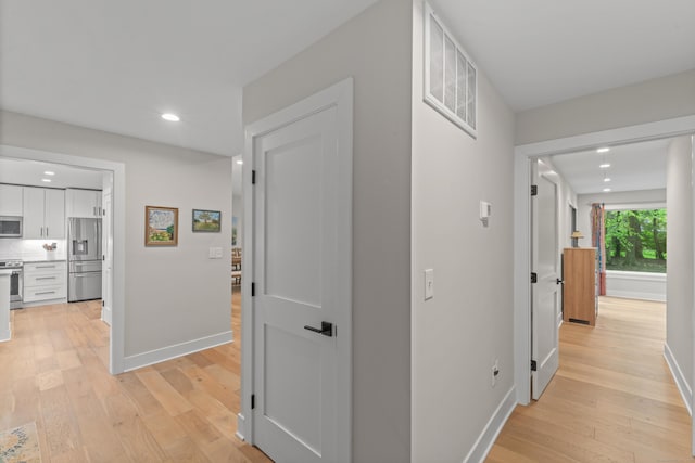 hallway featuring recessed lighting, baseboards, and light wood-style floors
