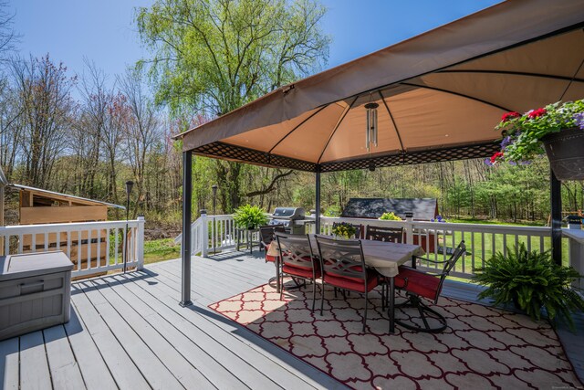wooden terrace featuring grilling area, a gazebo, and outdoor dining space