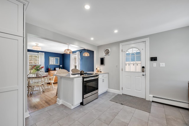 kitchen with a peninsula, a healthy amount of sunlight, stainless steel electric range, white cabinets, and a baseboard radiator