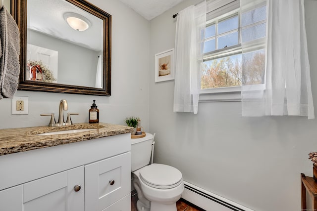 bathroom featuring vanity, a baseboard heating unit, and toilet
